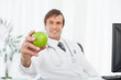 Green apple being held by a relaxed doctor