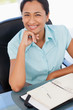Foto: Smiling secretary placing her hand on her chin while working Smiling secretary placing her hand on her chin while working