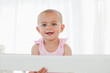Smiling baby standing in her bed while looking at the camera