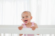 Beautiful baby standing in her bed while shouting