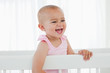 Little baby laughing in her white bed