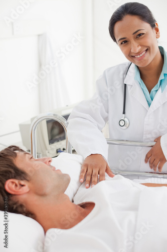 Photo: Smiling doctor looking at the camera while standing in a hospital room Smiling doctor looking at the camera while standing in a hospital room