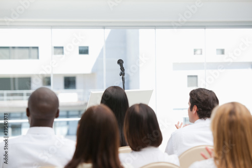 Photo: Colleagues sit while watching a microphone Colleagues sit while watching a microphone