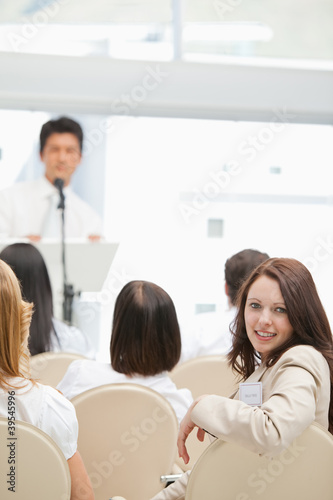 Photo: Happy brown haired woman looking behind her during a speech Happy brown haired woman looking behind her during a speech