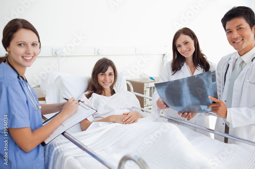 Photo: Smiling doctors looking ahead as they hold an x-ray scan with a patient Smiling doctors looking ahead as they hold an x-ray scan with a patient