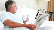 Man reading a newspaper in his bed