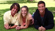 Woman laughing while lying on the grass before her friends roll in next to her