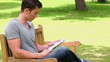 Video: Man reading a newspaper while sitting on a wooden bench Man reading a newspaper while sitting on a wooden bench