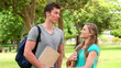 Video: Two friends talking to each other before looking at the camera as they stand in a park Two friends talking to each other before looking at the camera as they stand in a park