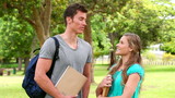 Video: Two friends talking to each other before looking at the camera as they stand in a park Two friends talking to each other before looking at the camera as they stand in a park