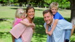 Boy runs and jumps onto his fathers back who gives him a piggy-back