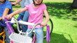 A boy and a girl sitting next to each otehr on bikes in a park