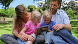Video: Family sitting next to each other while using a tablet pc which is being held by the children Family sitting next to each other while using a tablet pc which is being held by the children