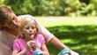 Mother and daughter in slow motion blowing a dandelion