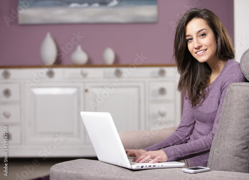 Photo: portrait of young woman on the sofa using laptop portrait of young woman on the sofa using laptop