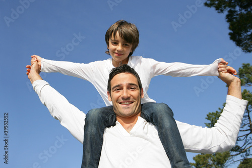 Photo: Child riding on his father's shoulders Child riding on his father's shoulders