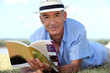 Elderly man reading a book outside