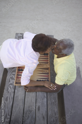 Photo: Senior couple kissing over game of backgammon Senior couple kissing over game of backgammon