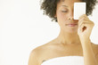 Woman wrapped in towel holding soap over eye