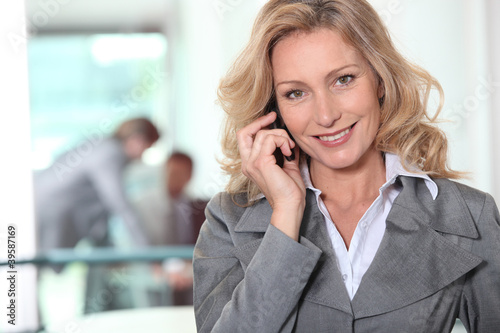 Photo: Businesswoman using a cellphone in an office Businesswoman using a cellphone in an office