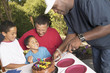Man cutting birthday cake with family