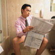 Businessman reading newspaper while sitting on toilet
