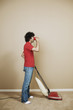 Young man drinking beer as he vacuums