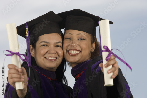 Photo: Two female graduates holding diplomas Two female graduates holding diplomas