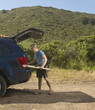 Man packing surfboard into SUV