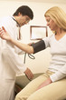 Asian male doctor taking patient's blood pressure