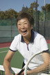 Senior Asian woman laughing on tennis court