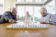 Portrait of three elderly men sitting at table playing game