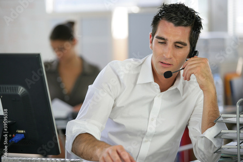 Photo: Young man telemarketer in call center Young man telemarketer in call center