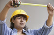Woman construction worker with measuring tape and hard hat