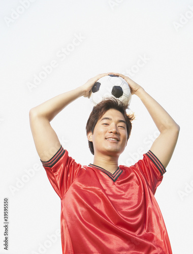 Photo: Portrait of soccer player holding ball on top of head Portrait of soccer player holding ball on top of head
