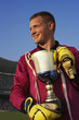 Male goalie triumphantly holding trophy