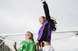 Two girls cheering in front of soccer net