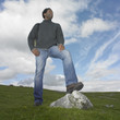 Man standing with one foot on a rock