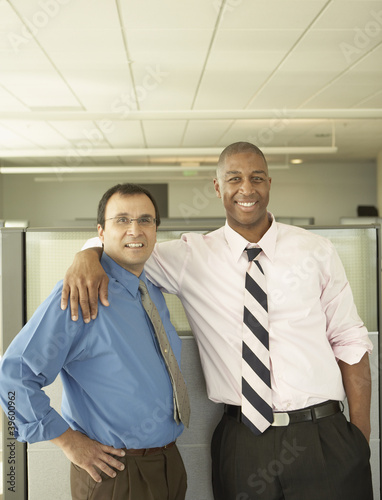 Photo: Businessmen smiling for the camera in empty office space Businessmen smiling for the camera in empty office space