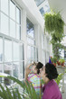 Mother and daughter looking out window of greenhouse