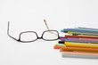 Farbige Buntstifte mit der Brille close-up.