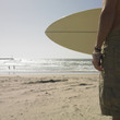 Man holding surf board at beach