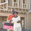 Portrait of couple standing by sold sign