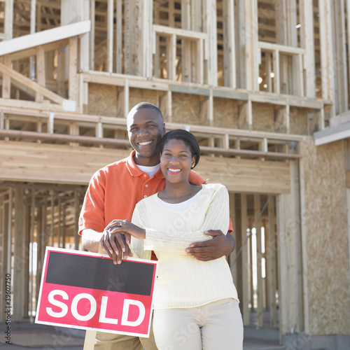 Photo: Portrait of couple standing by sold sign Portrait of couple standing by sold sign