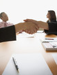 Businesspeople shaking hands across table