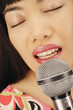 Close up of Asian woman singing into microphone