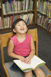 Laughing little girl reading a library book