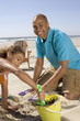 Portrait of father and daughter playing in sand at beach