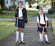 Portrait of sisters wearing uniforms on scooters