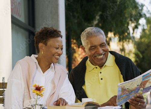 Photo: Senior couple looking at map while sitting at table Senior couple looking at map while sitting at table